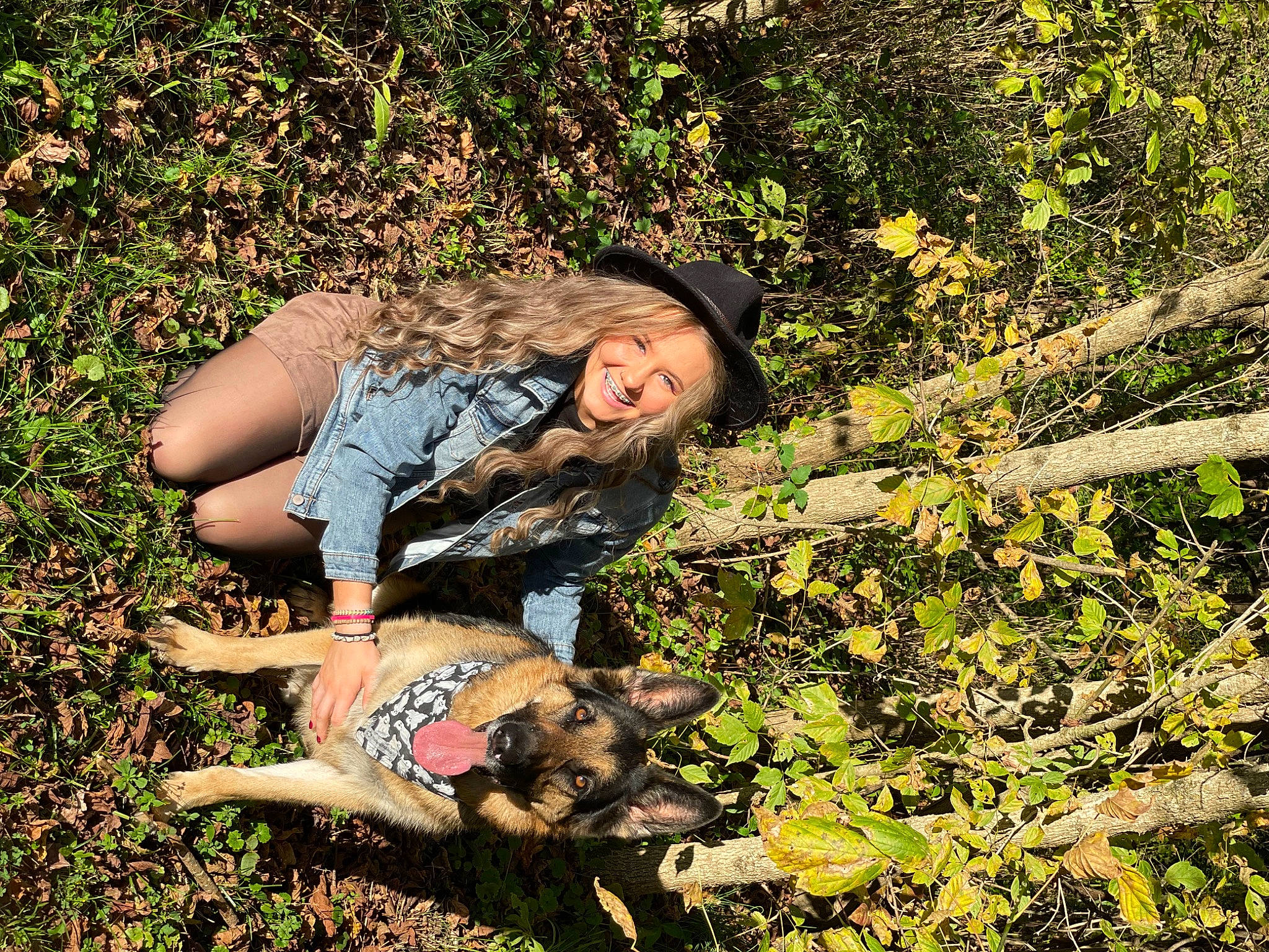 Bruno is registered to the contest to win money with this photo: boot, carnivore, dog_breed, grass, grassland, happy, hat, human_leg, landscape, leisure, luggage_and_bags, people_in_nature, plant, sitting, smile, soil, sun_hat, sunlight, thigh, wilderness