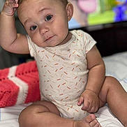 Londyn joined the competition — help win amazing prizes! baby, child, infant, onesie, bed, blanket, hand, foot, face, eyes, expression, skin, sitting, indoors, soft_focus, cute, portrait, person, background_blur, curious