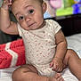 baby, child, infant, onesie, bed, blanket, hand, foot, face, eyes, expression, skin, sitting, indoors, soft_focus, cute, portrait, person, background_blur, curious