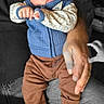 Zaylen is registered to the contest to win money with this photo: adult_hands, baby, black_and_white_background, blue_outfit, brown_pants, chair, child, close_up, clothing, colorful, cute, family_photo, hands, indoor, infant, portrait, sitting, text_overlay, three_months, wide_eyes