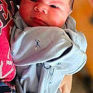 Zaylen is registered to the contest to win money with this photo: baby, newborn, infant, onesie, clothing, person, holding, red_shirt, closeup, face, portrait, indoor, human, cute, child, newborn_baby, baby_clothes, baby_face, soft_lighting, warm