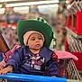 Azavia joined the competition — help win amazing prizes! baby, child, shopping_cart, hat, beanie, purple_sweater, fox_graphic, indoor, shopping, aisle, grocery_store, blurred_background, cute, chubby_cheeks, clothing, seat_belt, red_bell, pink_blanket, person, portrait