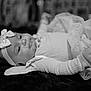 baby, black_and_white, bow, child, closeup, clothing, cute, dress, fabric, face, headband, indoors, infant, lying_down, newborn, peaceful, person, portrait, soft_focus, texture