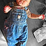 baby, baby_gear, casual_wear, child, clothing, cute, denim_overalls, expression, face, floor, footwear, hand, head, indoor, infant, person, portrait, skin, socks, young_child