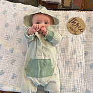 Gage is registered to the contest to win money with this photo: baby, infant, onesie, blanket, diaper, baby_wipes, wooden_sign, floor, carpet, green_clothing, footwear, cute, child, indoor, lying_down, person, baby_accessories, soft_texture, three_months, reaching_out