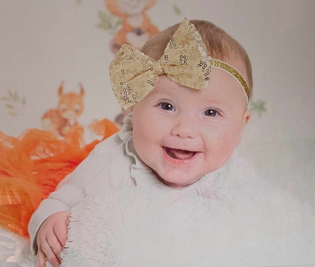 Evelyn joined the competition — help win amazing prizes! baby, smiling, headband, bow, blanket, orange, cute, animal_illustration, child, happy, portrait, infant, soft_texture, clothing, face, cute_expression, indoors, baby_girl, closeup, playful