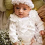 baby, infant, newborn, headband, flower_crown, white_dress, lace, flowers, bouquet, pillow, portrait, closeup, hands, eyes, soft_lighting, studio_photography, newborn_photography, floral_theme, cozy, peaceful