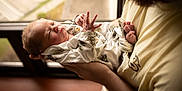 Dawson is registered to the contest to win money with this photo: newborn, baby, infant, person, holding, arms, window, light, indoors, clothing, sleeping, closeup, portrait, human, toddler, soft_light, cozy, adult, hands, cute