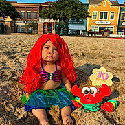 Ailany is registered to the contest to win money with this photo: child, baby, mermaid_costume, red_wig, crab_toy, sand, beach, boardwalk, outdoor, portrait, pouting, sitting, costume, colorful, sunlight, toy, birthday, ten_months, buildings, seaside