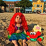 child, baby, mermaid_costume, red_wig, crab_toy, sand, beach, boardwalk, outdoor, portrait, pouting, sitting, costume, colorful, sunlight, toy, birthday, ten_months, buildings, seaside