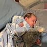 Ezio is registered to the contest to win money with this photo: baby, sleeping, onesie, polar_bear_pattern, plush_toy, elephant_plush, bed, pillow, blue_bedding, gray_bedding, infant, child, peaceful, indoors, soft_toy, red_ball, wooden_chair, wall, cozy, cute