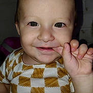 Ezio is registered to the contest to win money with this photo: baby, child, smiling, face, hand, finger, clothing, checkered_pattern, indoor, portrait, cute, young, person, skin, head, eyes, happy, infant, sitting, playful