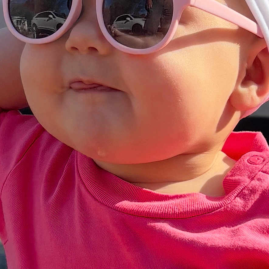 Sterlyn is registered to the contest to win money with this photo: accessory, baby, car, cheeky, child, closeup, cute, face, fashion, happy, headband, outdoor, person_reflection, pink_shirt, portrait, reflection, summer, sunglasses, sunlight, tongue