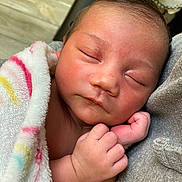 Jordan is registered to the contest to win money with this photo: newborn, baby, child, sleeping, blanket, fingers, hand, face, cheeks, cozy, close_up, portrait, swaddle, nap, peaceful, indoor, skin, tiny_hands, soft_fabric, caretaker_arm