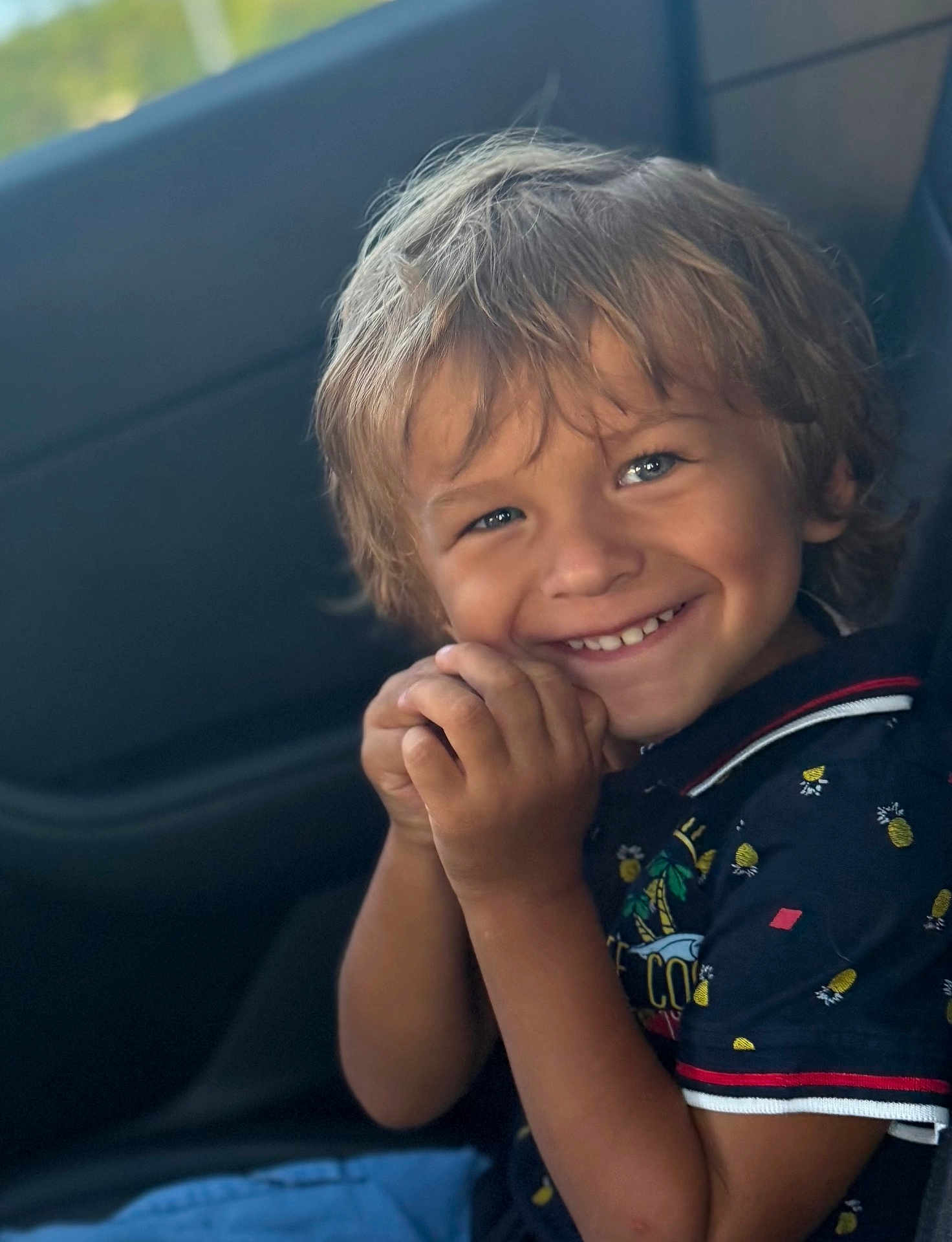 Marc participe au concours pour gagner de l'argent avec cette photo : child, smiling, happy, portrait, face, hands, car, seat, clothing, short_sleeve, patterned_shirt, blue, blond_hair, young, person, casual, cute, bright_eyes, indoor, close_up