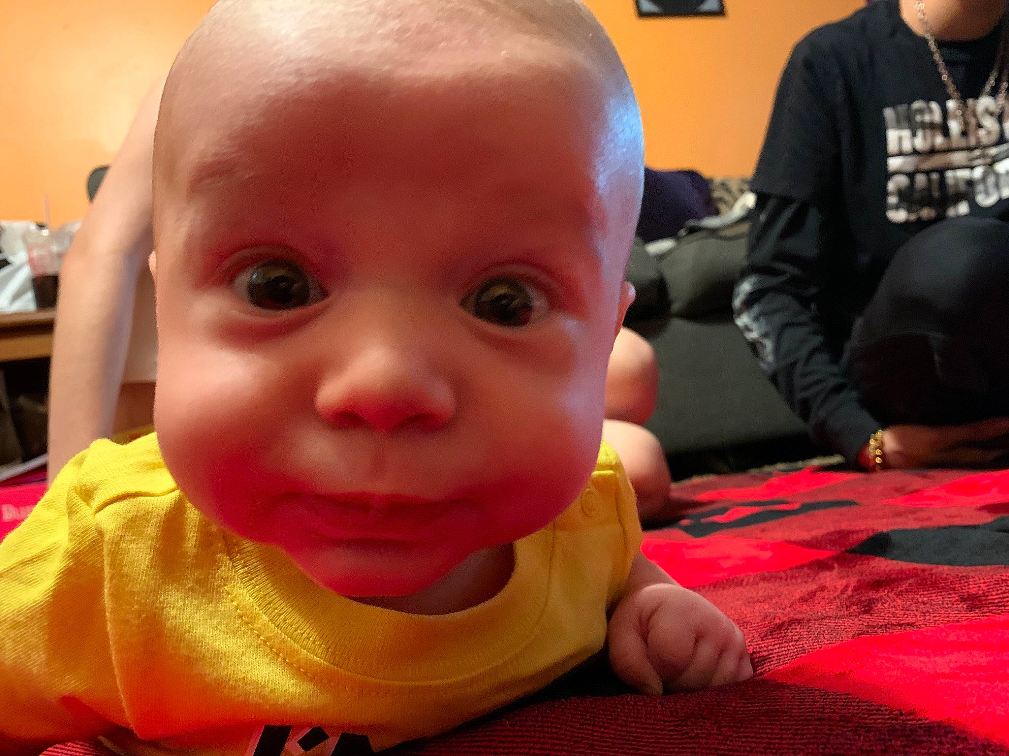 Kodi is registered to the contest to win money with this photo: baby, baby_toddler_clothing, carmine, cheek, child, eyebrow, facial_expression, finger, flooring, fun, happy, lip, mouth, nose, person, sitting, skin, smile, thumb, toddler