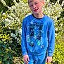 Kenzo participe au concours pour gagner de l'argent avec cette photo : child, boy, outdoor, greenery, flowers, blue_clothing, sweatshirt, pants, sneakers, smile, sunlight, nature, plant, grass, casual, portrait, standing, happy, daylight, young