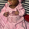 baby, infant, sleeping, pink_outfit, hat, bow, pacifier, onesie, child, portrait, indoors, bed, blanket, striped_bedding, soft_blanket, lying_down, peaceful, closed_eyes, baby_clothing, hello_world