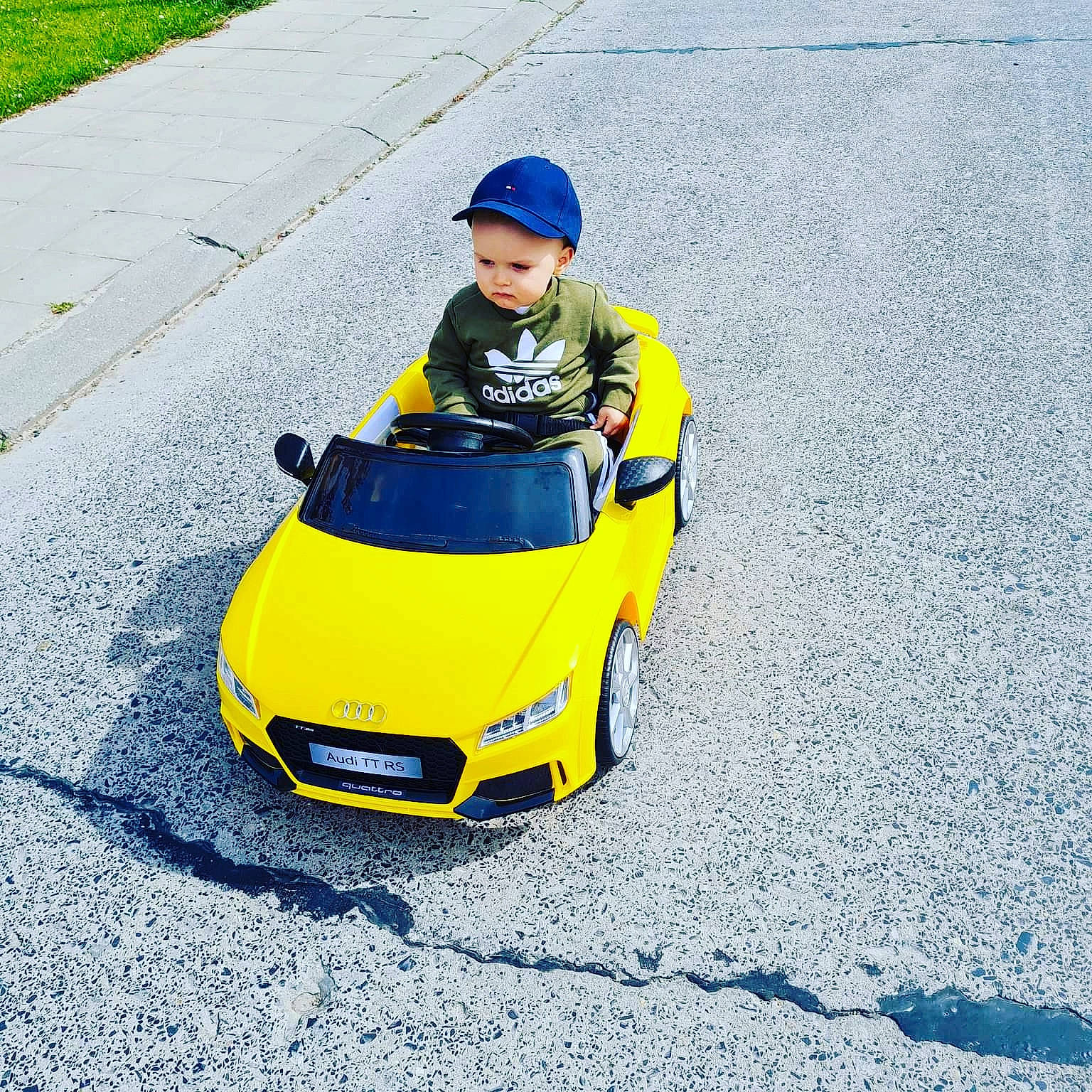 Gabin a rejoint le concours — aidez-le/la à gagner de superbes lots ! asphalt, automotive_design, automotive_exterior, automotive_lighting, automotive_tire, automotive_wheel_system, bumper, car, fender, grass, headlamp, headwear, helmet, hood, motor_vehicle, person, personal_luxury_car, road_surface, tire, toddler