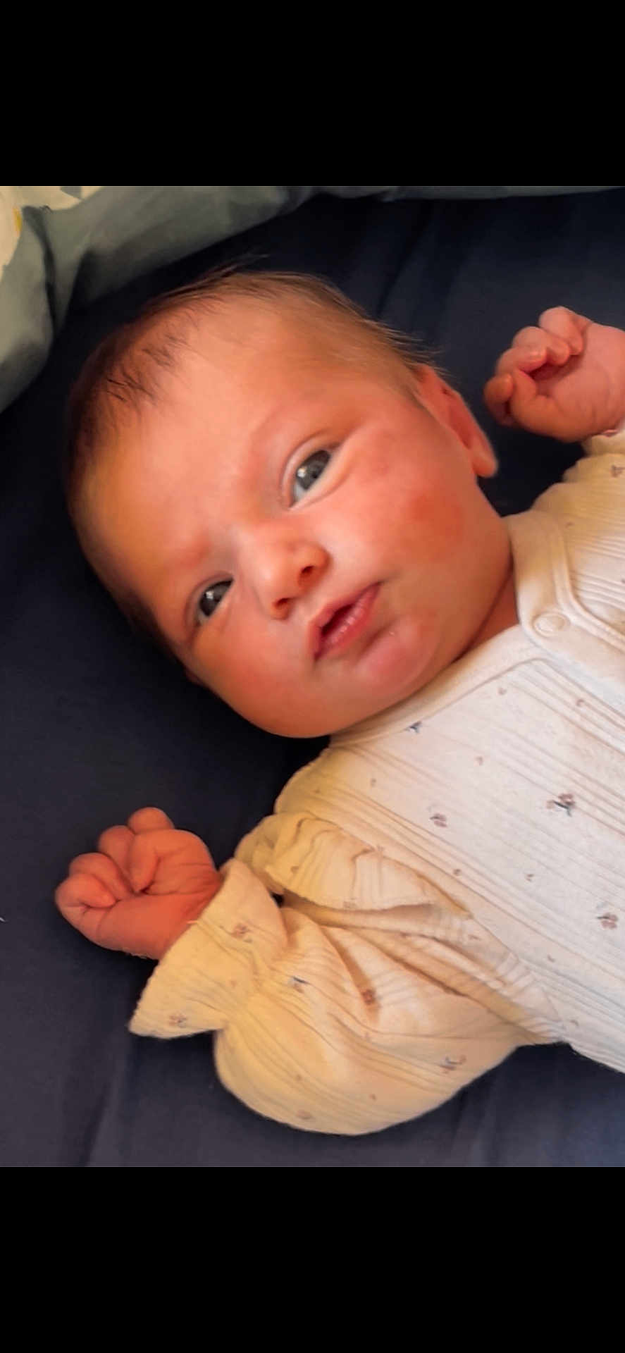 Lyanna a rejoint le concours — aidez-le/la à gagner de superbes lots ! baby, infant, newborn, face, eyes, hands, onesie, clothing, blanket, lying_down, portrait, cute, soft_skin, curious, child, person, indoors, sleepwear, resting, closeup