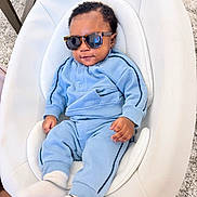 Samuel joined the competition — help win amazing prizes! baby, blue_tracksuit, book, carpet, child, clothing, comfortable, cool, cushion, cute, fashion, footwear, home, indoor, infant, person, portrait, relaxing, sunglasses, white_seat