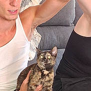 Galaxy participe au concours pour gagner de l'argent avec cette photo : person, cat, tortoiseshell_cat, couch, pillow, white_tank_top, curly_hair, arm, indoor, furniture, pet, holding, seated, cozy, curious, expression, closeup, casual, relaxed, home