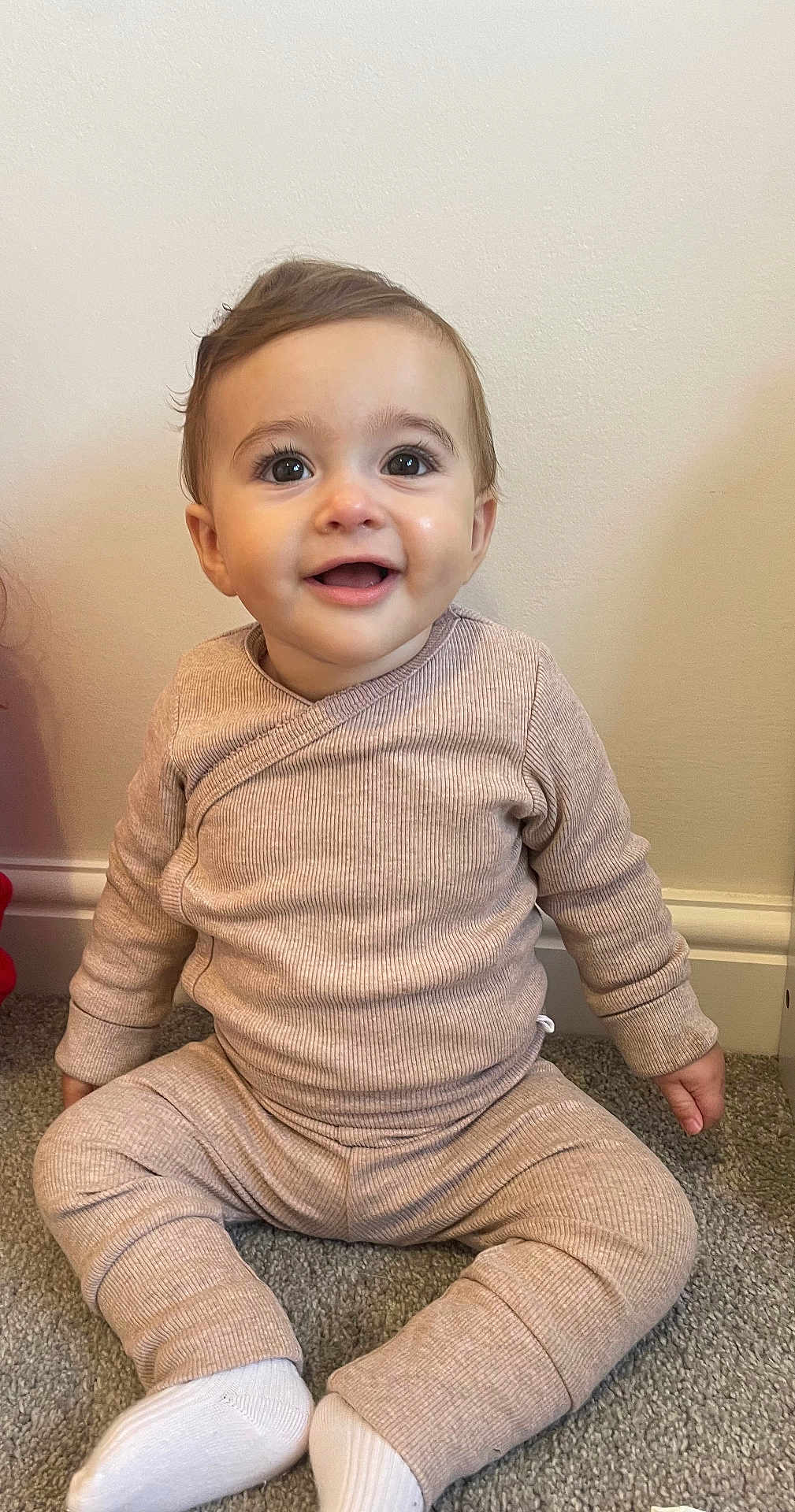 Arabella joined the competition — help win amazing prizes! baby, child, smiling, sitting, carpet, clothing, socks, indoor, face, person, long_sleeve, pants, cute, young, happy, infant, wall, floor, portrait, casual