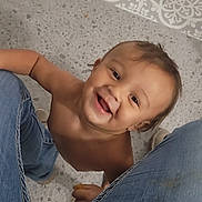 Tydus is registered to the contest to win money with this photo: toddler, child, smiling, jeans, floor, bare_chest, happy, person, indoor, looking_up, playful, casual, human, young_child, portrait, cute, baby, hands, feet, clothing