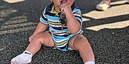 Tydus is registered to the contest to win money with this photo: baby, child, keys, playground, sitting, striped_clothing, socks, person, shadow, outdoor, curious, chewing, feet, legs, summer, sunlight, play, toy, casual, young