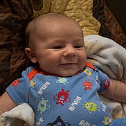 Steven Olivier is registered to the contest to win money with this photo: baby, blanket, blue_clothing, child, cozy, cute, happy, indoors, infant, laying_down, monster_print, onesie, person, portrait, quilt, relaxed, sleepwear, smiling, soft_texture, toddler