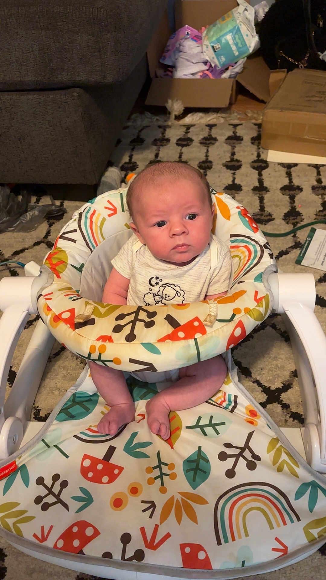 Steven Olivier joined the competition — help win amazing prizes! baby, infant, baby_seat, colorful, patterned, carpet, indoor, child, serious_expression, person, newborn, clothing, sitting, face, head, toes, footwear, home, box, furniture