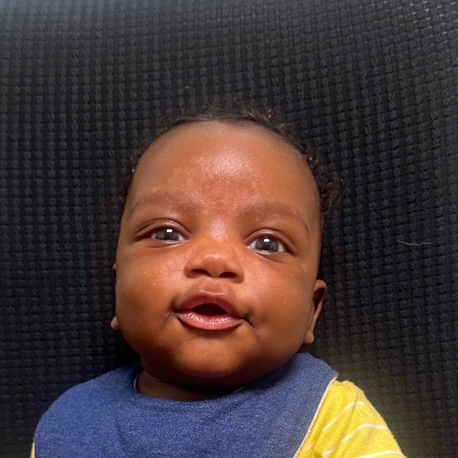 Makari joined the competition — help win amazing prizes! baby, background, bib, blue, child, closeup, clothing, cute, expression, eyes, face, indoor, infant, mouth, person, portrait, skin, smile, textured, yellow