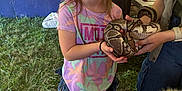 Marie is registered to the contest to win money with this photo: child, girl, smile, snake, reptile, grass, tent, person, adult, casual_clothing, shoes, jeans, outdoor, animal, hands, holding, happy, event, nature, interaction