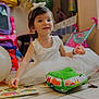 balloon, blackhair, bowl, child, clothing, dress, eating, face, female, festival, food, girl, hair, head, person, racket, sitting, sleeve, sport, toy