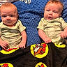 babies, baby_clothing, blue_blanket, cartoon_blanket, children, close_up, cozy, eyes, faces, family_photo, indoors, infants, lying_down, matching_outfits, onesies, plush_blanket, portrait, short_hair, sitting, twins