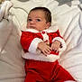 baby, infant, child, red_clothing, santa_outfit, holiday, blanket, white_blanket, cute, portrait, indoors, newborn, small_hands, soft_texture, warm_clothing, festive, christmas, relaxed, lying_down, face