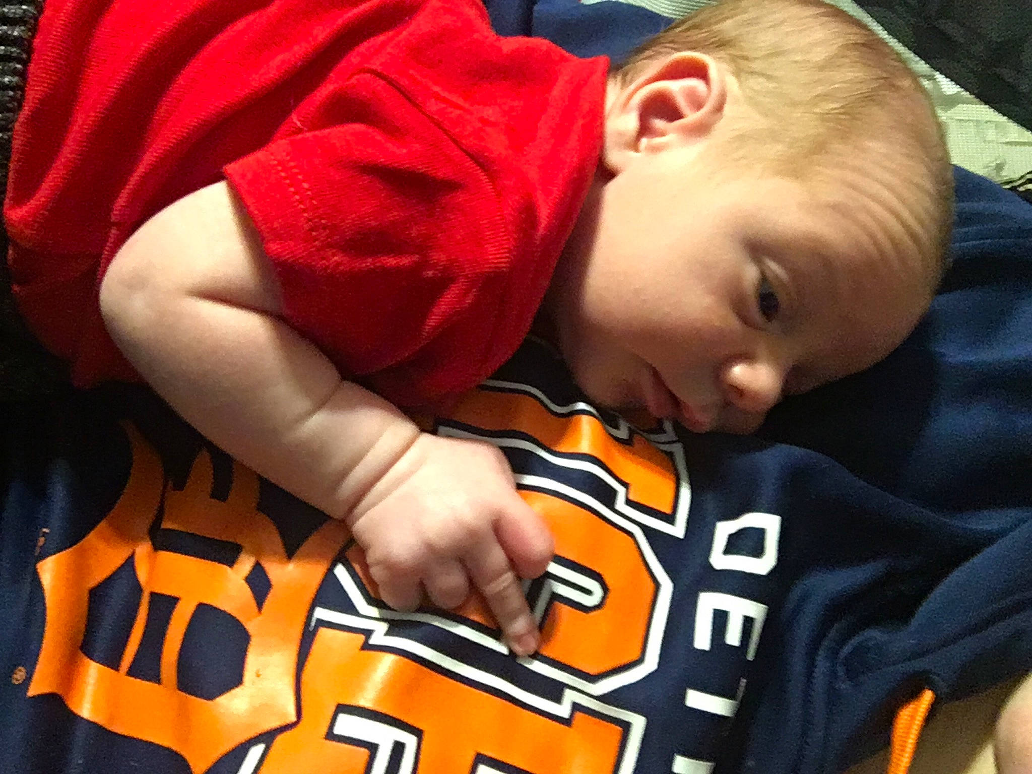 Olliver is registered to the contest to win money with this photo: baby, baby_toddler_clothing, child, comfort, cool, elbow, finger, gesture, happy, head, jersey, orange, people, person, photograph, product, sleeve, snapshot, sports_uniform, t_shirt