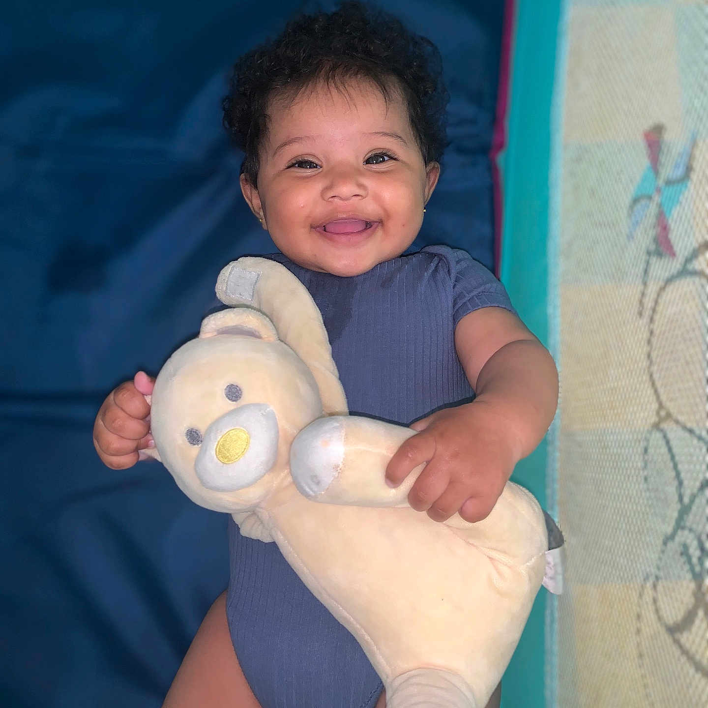 Mayla Ronisia participe au concours pour gagner de l'argent avec cette photo : adorable, baby, baby_toys, blue_onesie, child, childhood, cozy, cuddly_toy, curly_hair, cute, happy, indoor, infant, lying_down, person, playtime, plush_toy, portrait, smiling, soft_toy