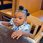 Miracle is registered to the contest to win money with this photo: toddler, child, baby, table, wood, restaurant, booth, chair, curly_hair, puffs, clothing, short_sleeves, indoor, window, daylight, seat, furniture, person, cute, exploring