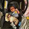 baby, infant, car_seat, blue_hat, bear_patch, socks, beige_pants, blanket, fabric, indoor, portrait, child, cute, cozy, resting, newborn, clothing, person, seat, casual