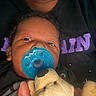 Messiah joined the competition — help win amazing prizes! baby, pacifier, stuffed_animal, hand, adult, clothing, face, portrait, closeup, black_shirt, purple_text, infant, child, person, indoor, comfort, cuddle, cute, young, holding
