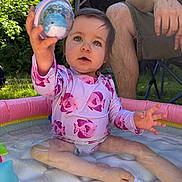Amelie is registered to the contest to win money with this photo: adult, backyard, child, curious, fish_pattern, grass, inflatable_pool, legs, nature, outdoor, pink, play, pool, sitting, summer, sunlight, swimsuit, toddler, toy, water