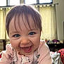 Amelie is registered to the contest to win money with this photo: baby, smiling, indoor, child, onesie, cute, happy, face, portrait, blue_eyes, hair, infant, close_up, window, curtains, bedroom, soft_lighting, pink_clothing, animal_print, joyful