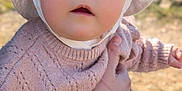 Tessa a rejoint le concours — aidez-le/la à gagner de superbes lots ! baby, child, face, bonnet, knitted_sweater, pink_clothing, hand, outdoor, natural_light, portrait, cute, infant, person, closeup, soft_texture, calm, curious, holding, skin, young