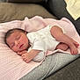 baby, newborn, sleeping, blanket, pink, cushion, polka_dots, pillow, white_clothing, infant, peaceful, resting, indoors, soft_texture, cute, small_hands, small_feet, face, relaxation, cozy