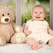Aaron a rejoint le concours — aidez-le/la à gagner de superbes lots ! baby, teddy_bear, smiling, indoor, soft_toy, carpet, child, cute, overalls, plush, happy, portrait, infant, sitting, face, toy, window, background, furniture, homedecor