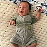 baby, infant, smile, happy, onesie, clothing, blanket, pattern, blue, green, face, hand, foot, lying_down, cute, child, person, indoors, portrait, playful