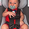 Luka joined the competition — help win amazing prizes! baby, child, car_seat, pacifier, curly_hair, red_clothing, mickey_mouse, straps, sitting, infant, blue_eyes, cute, safety_harness, indoors, plush, legs, hands, closeup, portrait, young