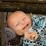 Grayson joined the competition — help win amazing prizes! baby, smiling, infant, patterned_clothing, rolled_blanket, wooden_box, soft_texture, happy, portrait, closeup, child, cute, cozy, indoor, person, newborn, baby_hands, fabric, warm, resting