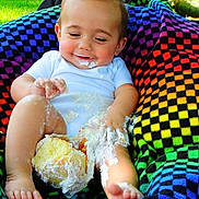 Ashton joined the competition — help win amazing prizes! baby, cake, frosting, smiling, colorful_blanket, outdoor, grass, child, messy, happy, feet, legs, white_shirt, food, celebration, nature, cute, playful, portrait, sitting